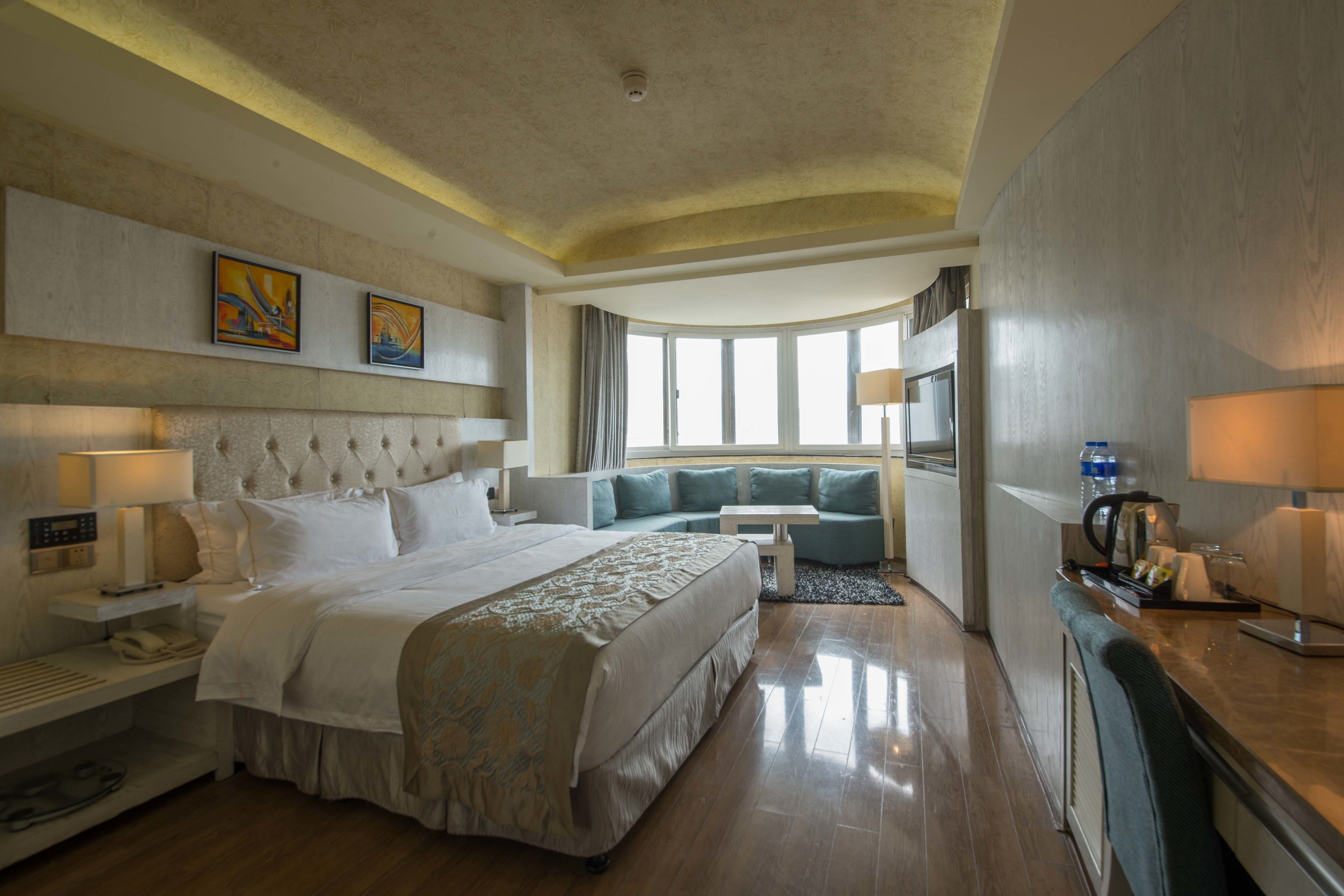 A hotel room with a large bed, a sofa, a desk, and a view of the outdoors.