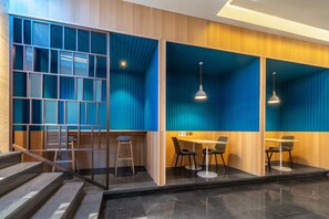 A modern interior with a staircase, a seating area with tables and chairs, and a blue and wooden color scheme. - Holiday Inn Express Xiamen Lushan by IHG (Xiamen)
