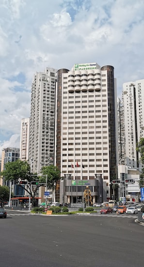A high-rise hotel with multiple floors and balconies, surrounded by other tall buildings. - Holiday Inn Express Xiamen Lushan by IHG (Xiamen)