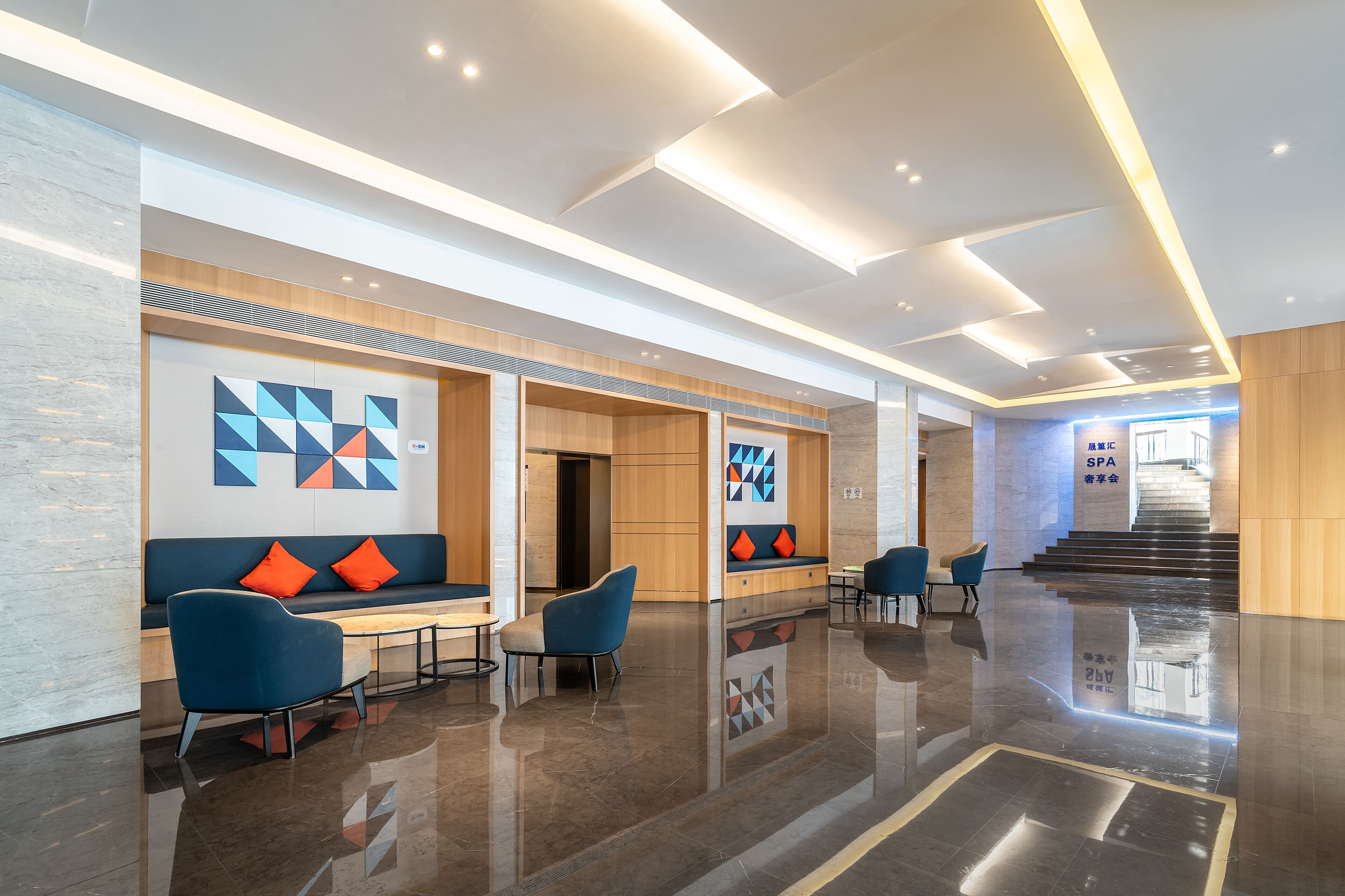 Een moderne lobby met een zithoek, een trap en een bord met de tekst 'Spa'.