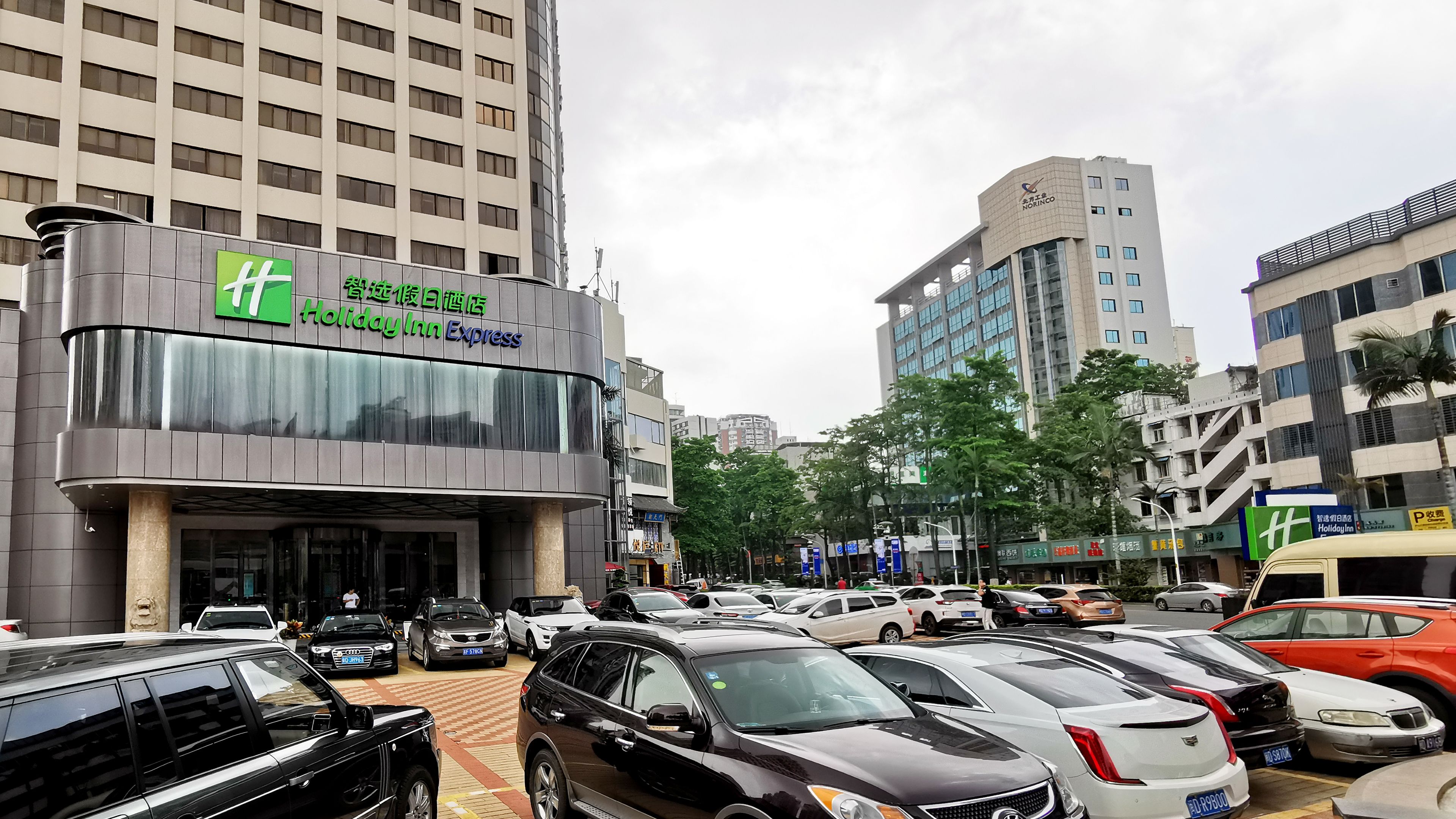 A Holiday Inn Express building with a modern design, featuring a prominent sign and a parking lot with various cars.