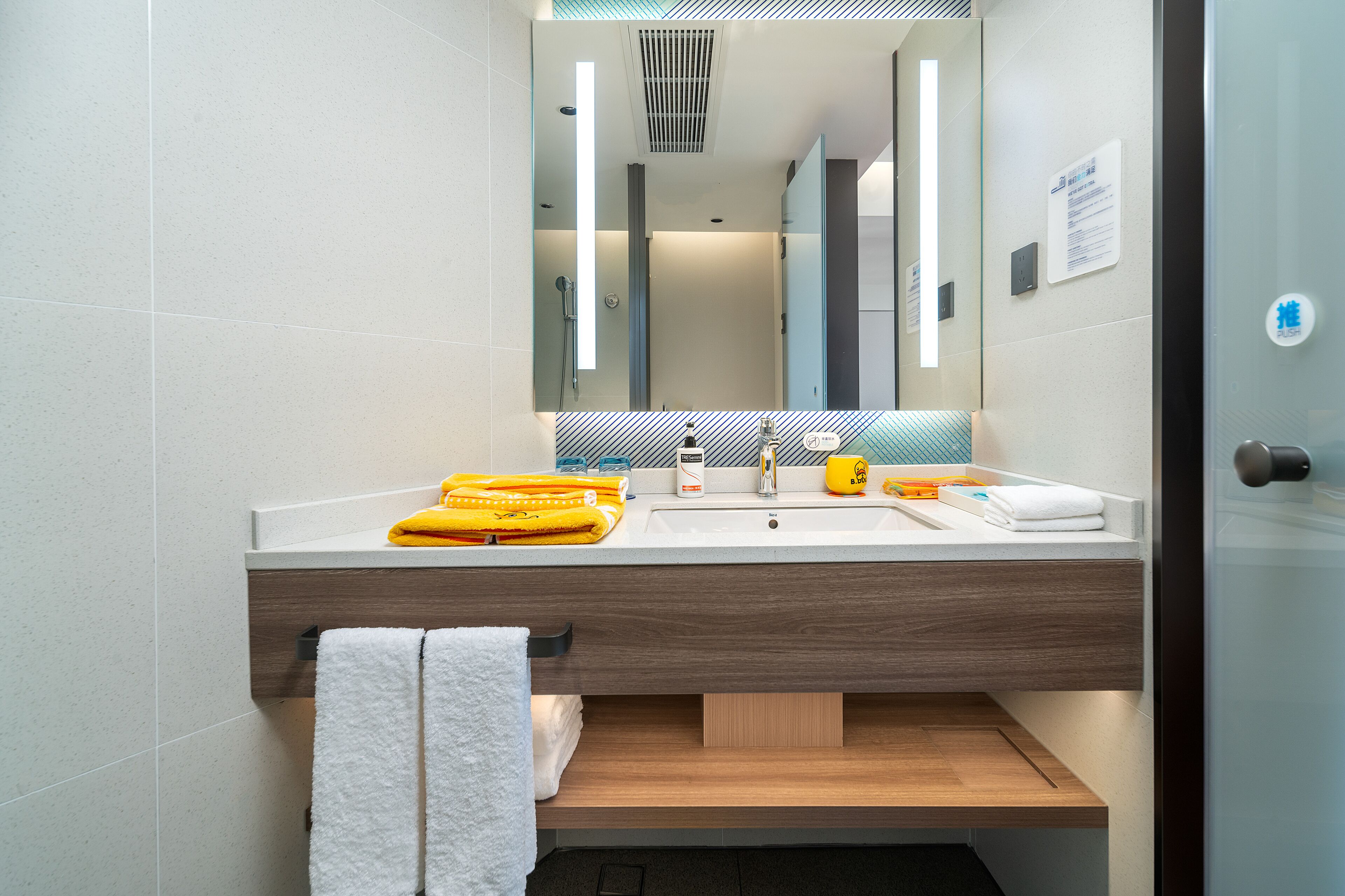 A modern bathroom with a large mirror, a sink, and a towel rack.