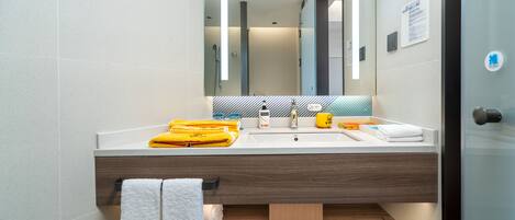 A modern bathroom with a large mirror, a sink, and a towel rack.