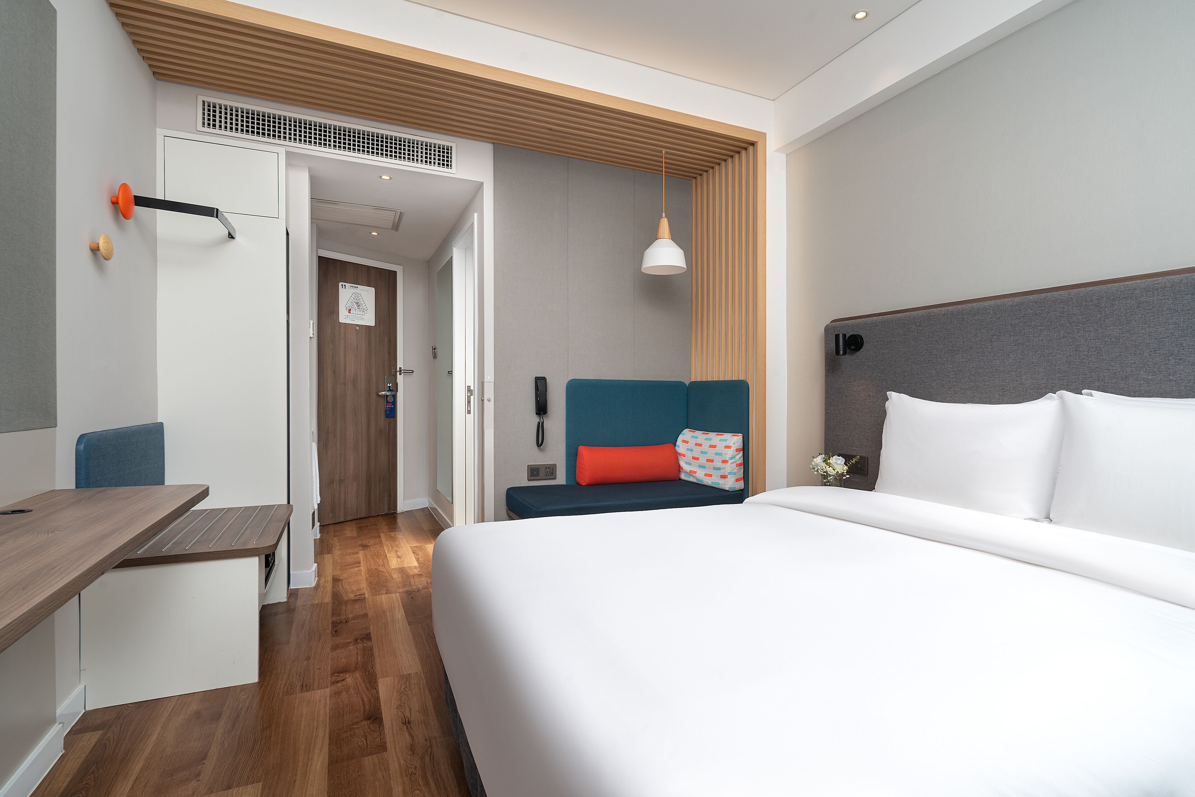 A modern hotel room with a large bed, a desk, and a seating area.