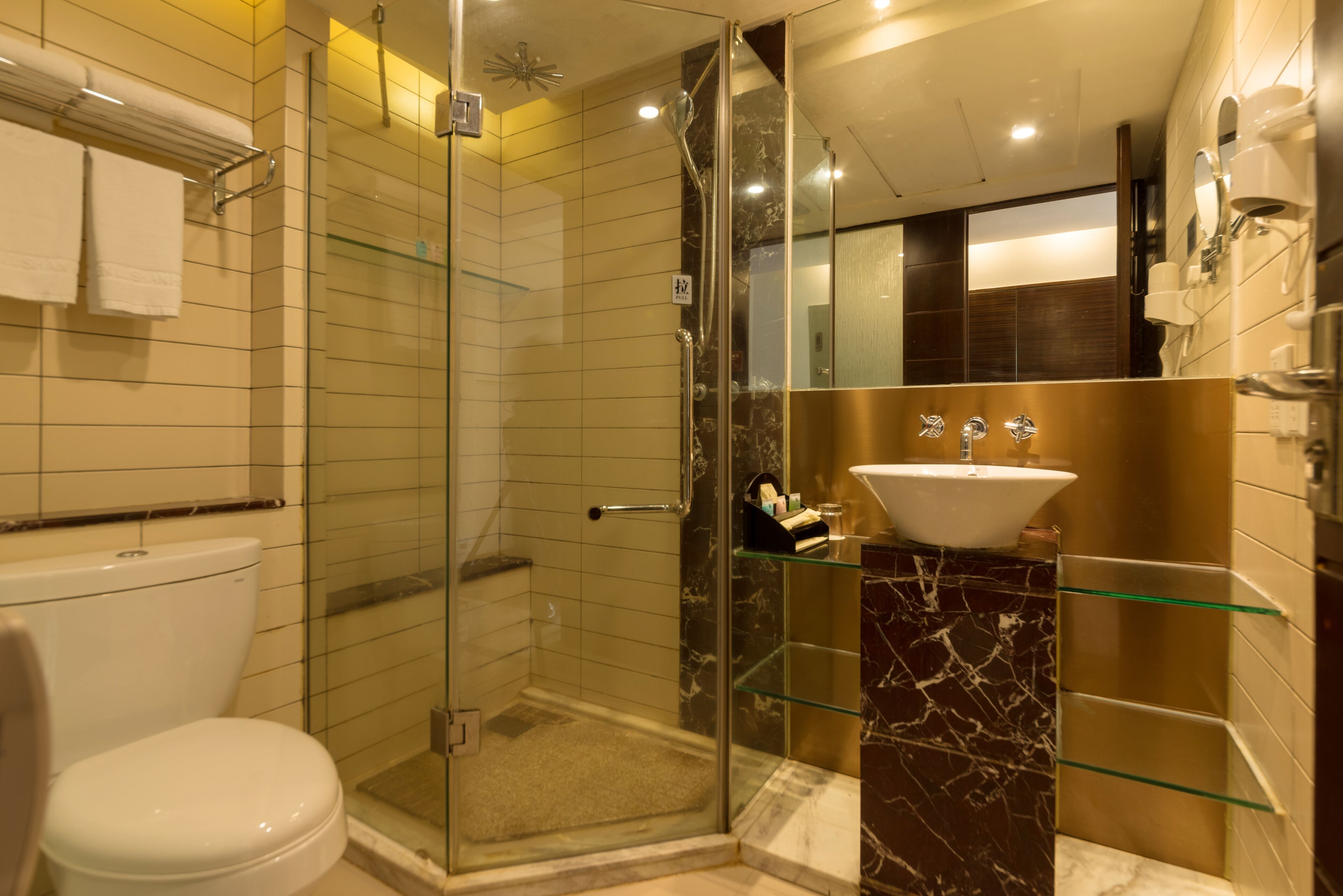 A modern bathroom with a glass-enclosed shower, a white toilet, and a marble sink.