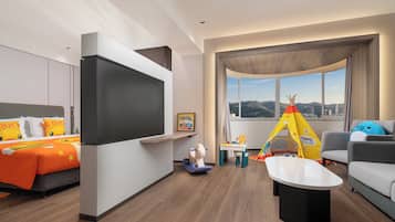 Une chambre d’hôtel moderne équipée d’un lit, d’une télévision, d’un canapé, d’une petite table et d’une fenêtre donnant sur un paysage agréable.
