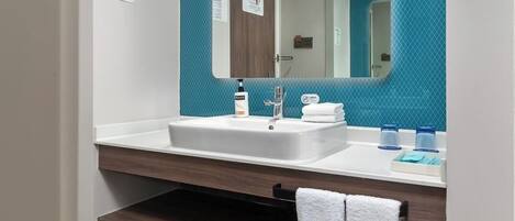 Un baño con un lavamanos blanco, un espejo y un perchero para toallas.