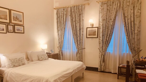 A hotel room with a bed, bedside table, lamp, and a rug. - The Elgin Fairlawn Kolkata (Kolkata)