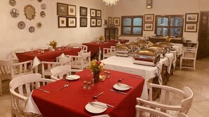 A dining area with multiple tables set for service, white chairs, and a variety of framed pictures on the walls. - The Elgin Fairlawn Kolkata (Kolkata)
