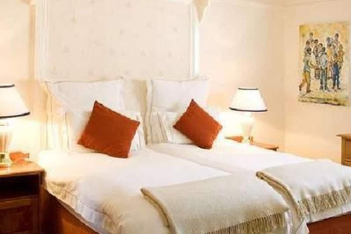 Habitació d'hotel amb un llit amb cortines, dues taules de nit i un quadre a la paret.