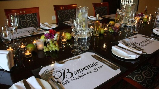 A dining table set with a menu card, glasses, cutlery, and candles. - Benvenuto Conference and Train (Randburg)