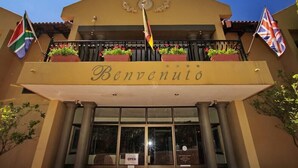 A building with a balcony, a sign reading "Benvenuto," and flags. - Benvenuto Conference and Train (Randburg)