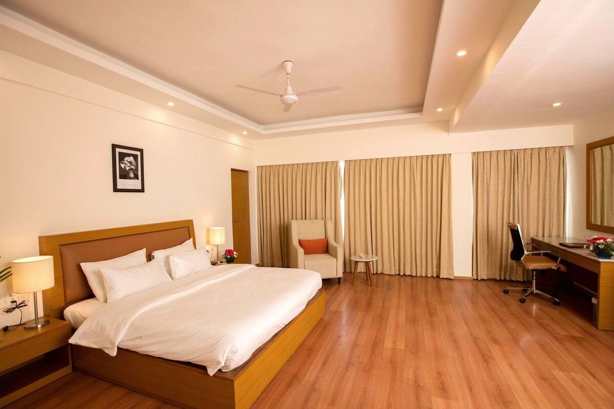 A hotel room with a bed, desk, chair, and a ceiling fan.