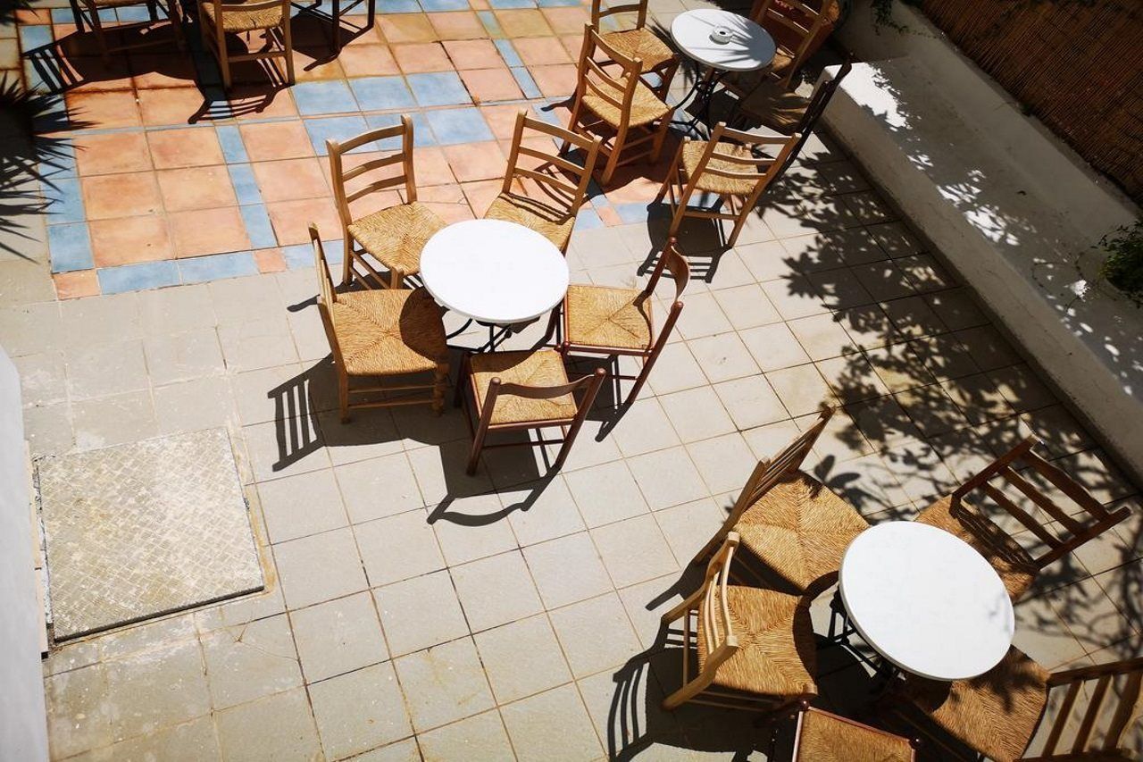 An outdoor patio area with multiple round tables and wooden chairs.
