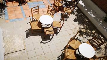 An outdoor patio area with multiple round tables and wooden chairs.