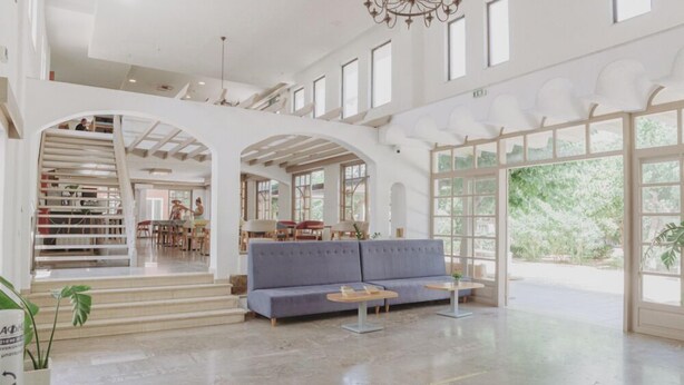 A spacious lobby with a blue sofa, two small tables, and a staircase leading to another level. - Apollon (Agios Nikolaos)