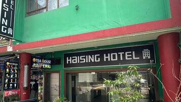 Un edificio de dos pisos con fachada verde y un letrero que dice Haising Hotel.