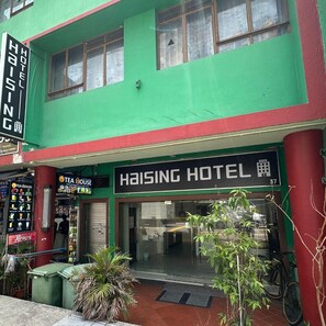 A two-story building with a green facade and a sign for Haising Hotel. - Haising (SINGAPORE)