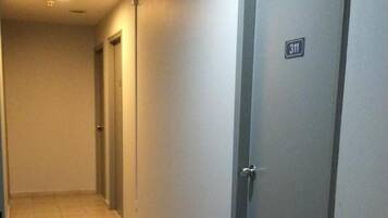Un pasillo con suelo de baldosas, una puerta marcada con el número 311 y otra puerta con manija.