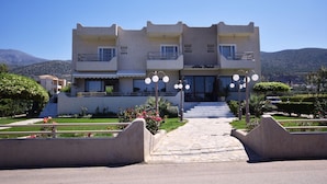 A hotel with a symmetrical facade, multiple balconies, and a central entrance with steps. - Altis Hotel (Malia)