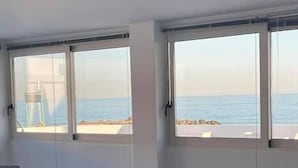 Comedor con mesas y sillas, ventanas amplias con vista al mar.