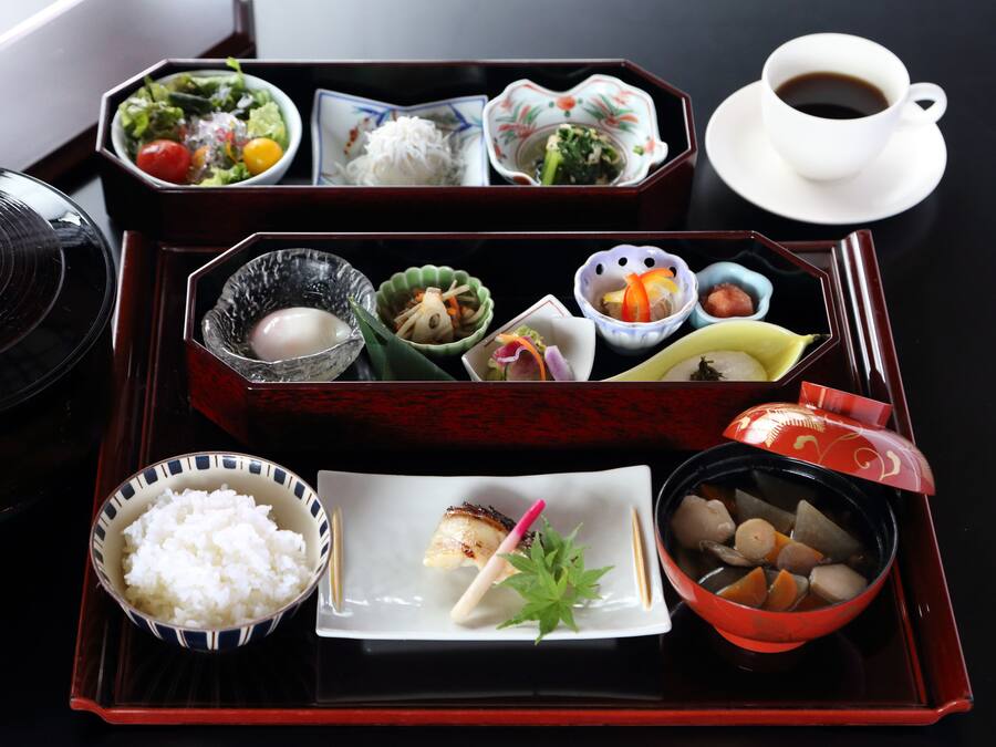 A traditional Japanese meal set on a tray with various dishes including rice, soup, and vegetables.