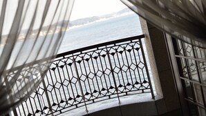 A view from a balcony with a metal railing and sheer curtains, overlooking a body of water and distant land. - Kamakura Park Hotel (Kamakura)