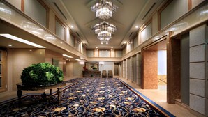 A spacious lobby with a patterned carpet, a large chandelier, and a potted plant. - Kamakura Park Hotel (Kamakura)