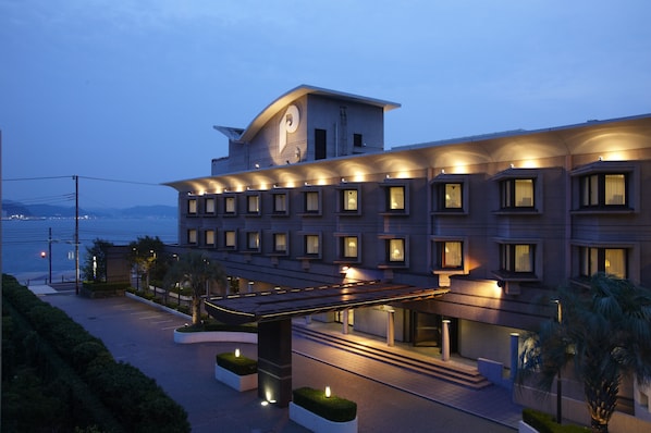 Un hotel moderno con una imponente torre de reloj, varios balcones y vistas al agua.