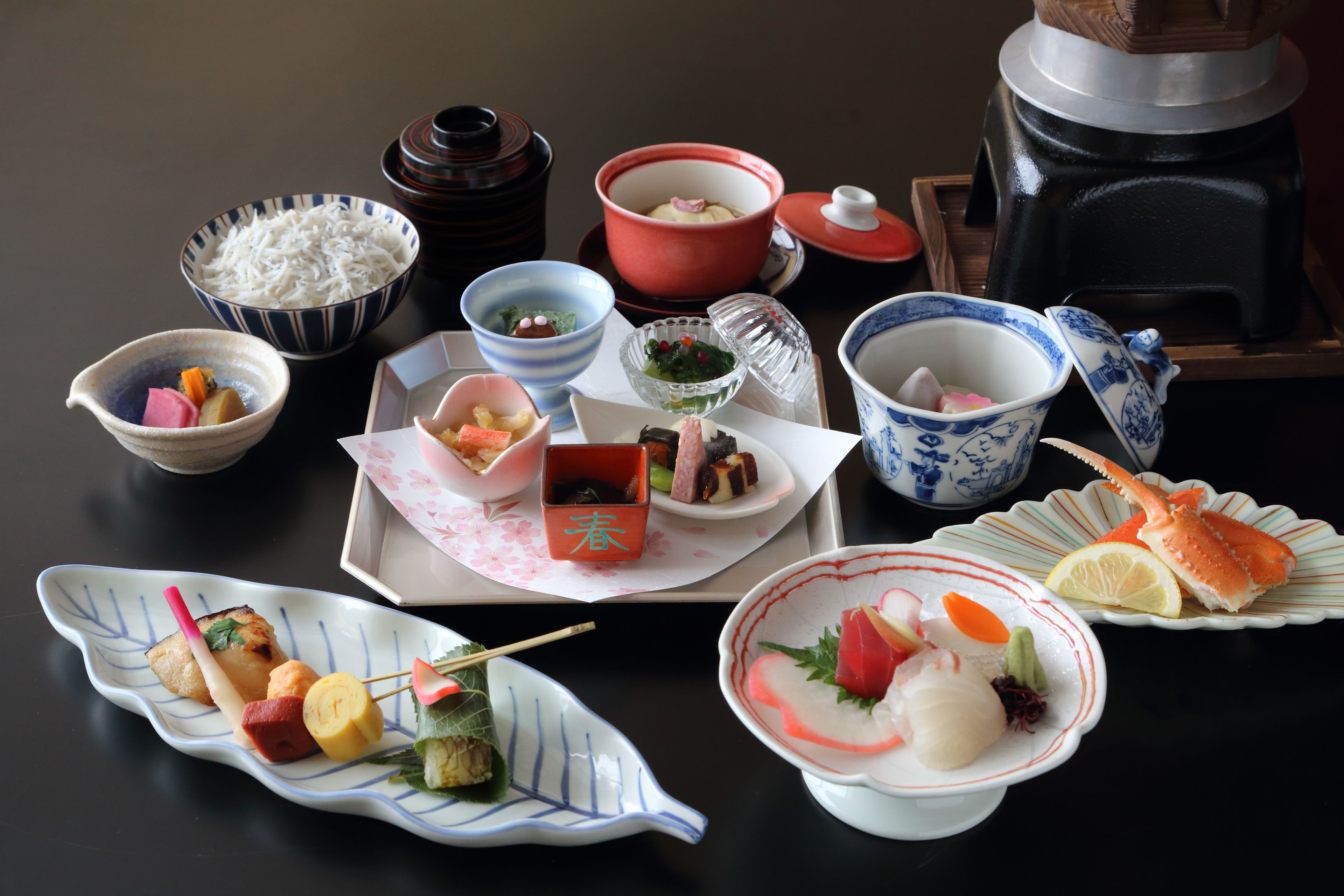 Diverse Japanse gerechten, waaronder sushi, sashimi en rijstkommen, op een tafel.