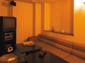 Un salon comprenant un canapé, une table basse, un téléviseur et une petite étagère ornée d’objets décoratifs.