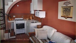 Eine kompakte Küche mit Herd, Backofen und Mikrowelle, einem Spülbecken und einer kleinen Essecke mit Stuhl und Tisch.