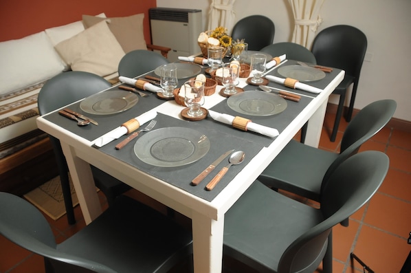 A dining table set with plates, cutlery, and glasses, surrounded by chairs.