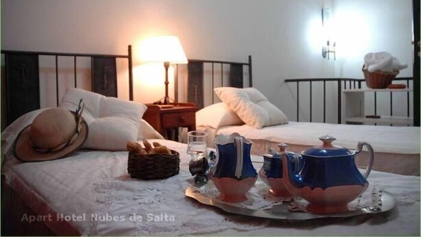 Ein Hotelzimmer mit einem Bett, einem Nachttisch mit Lampe und einem Tablett mit Teekannen und einem Korb.