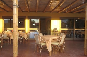 Un espace de restauration en plein air agrémenté de piliers, de tables et de chaises en bambou et en osier.
