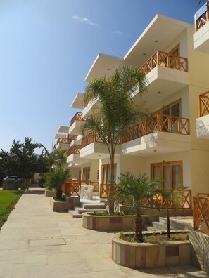A multi-story hotel with balconies, outdoor seating, and palm trees. - Hotel Emancipador (Ica)