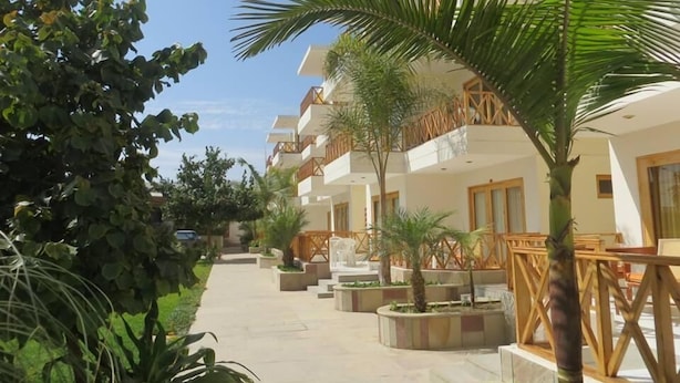 Un hotel con varios balcones, zonas de estar al aire libre y un camino central.