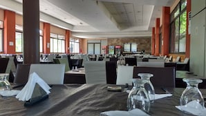 Um restaurante espaçoso com várias áreas de refeição, grandes janelas e um design de interiores moderno.