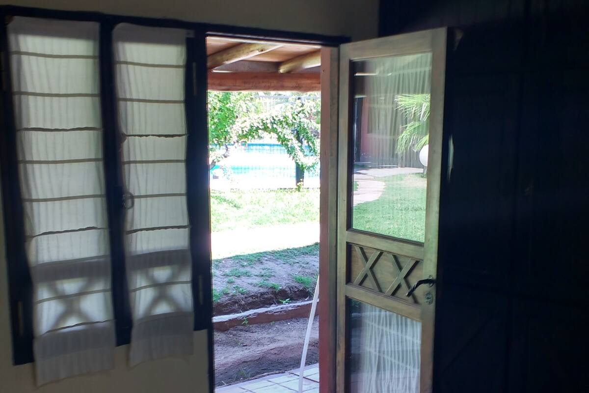 A room with a bed, a table, and a door leading to an outdoor area.