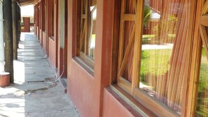 Um corredor coberto com vigas de madeira e amplas janelas com cortinas.