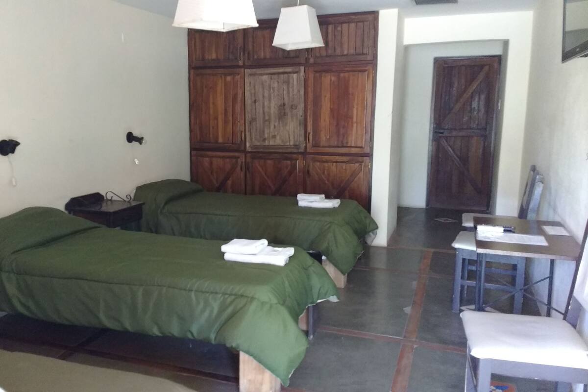 A room with two beds, a desk, and a chair.