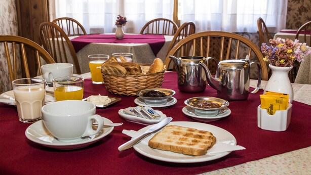 Ein Frühstückstisch mit Brot, Butter, Marmelade, Kaffee und Tee.