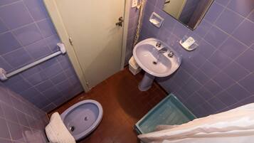 Un baño con lavamanos, inodoro y zona de ducha.