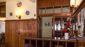 Un mostrador de recepción de madera con un florero y una lámpara de pared, además de un cuadro enmarcado.