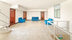 Un vestíbulo espacioso con un sofá azul, una escalera y un letrero que indica zona prohibida para fumadores.