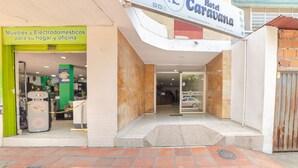 Entrada de un hotel con un letrero que indica Hotel Caravana y una tienda llamada Muebles y Electrodomésticos.