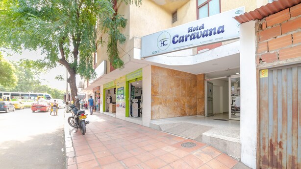 Un hotel llamado 'Hotel Caravana' con un vestíbulo adoquinado y una motocicleta estacionada afuera.