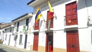 Un bâtiment blanc avec des portes et des fenêtres rouges, portant l’inscription « Hôtel Poyayan Plaza ».