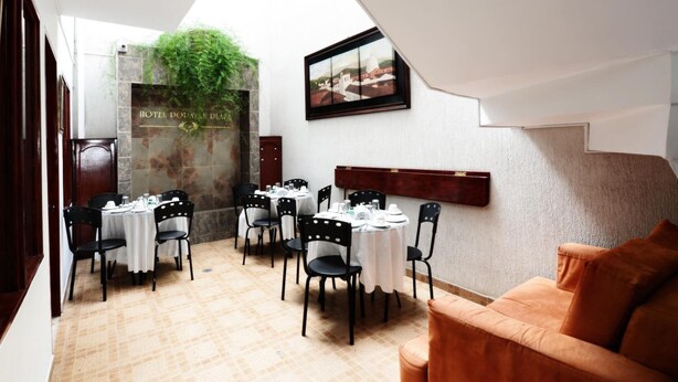 Un coin repas avec des tables dressées pour le repas, un canapé et un tableau accroché au mur.