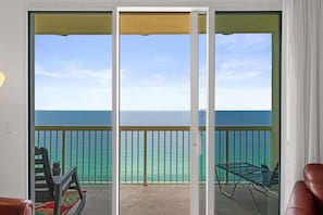 Un balcone con vista sull'oceano, una sedia e un tavolo.